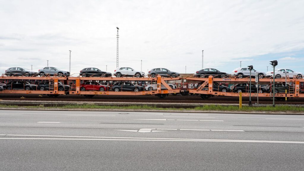 Güterzug mit doppelstöckigen Waggons voller Neuwagen im Hafengebiet