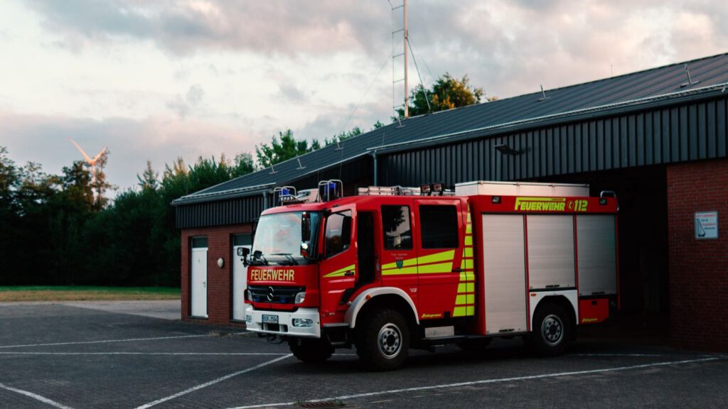 Rotes Feuerwehrfahrzeug vor einer Feuerwache bei Sonnenuntergang
