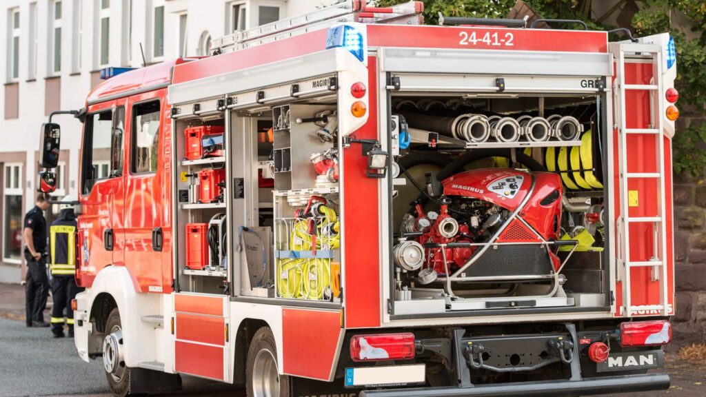 Feuerwehrfahrzeug mit geöffneten Geräteräumen voller Ausrüstung am Straßenrand