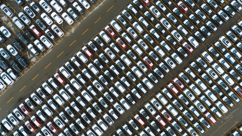 Luftbild einer großen Parkfläche mit dicht in Reihen abgestellten Fahrzeugen