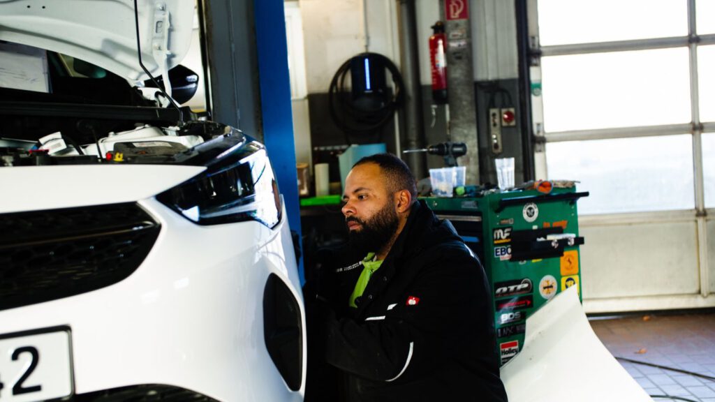 Mechaniker arbeitet in einer modernen Kfz-Werkstatt an einem Fahrzeug