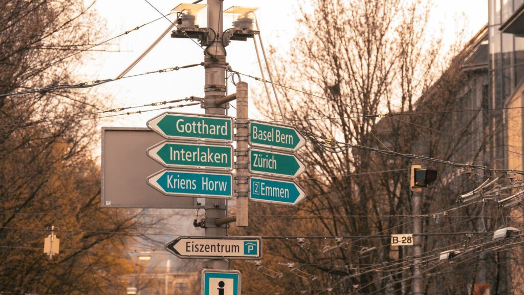 Straßenszene in Luzern mit grünen Wegweisern zu Schweizer Städten
