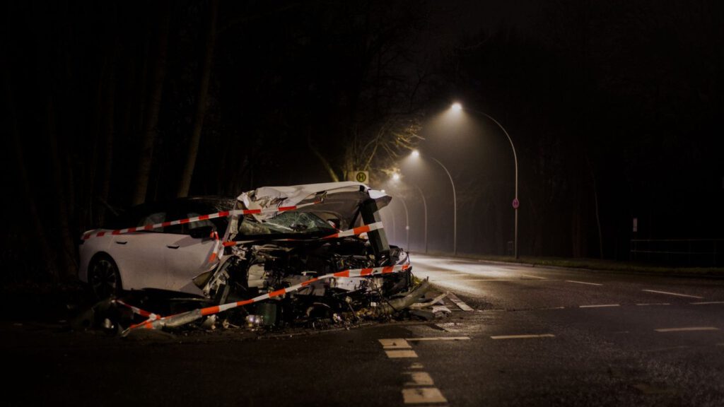 Stark beschädigtes Unfallfahrzeug mit Absperrband auf einer nächtlichen Straße